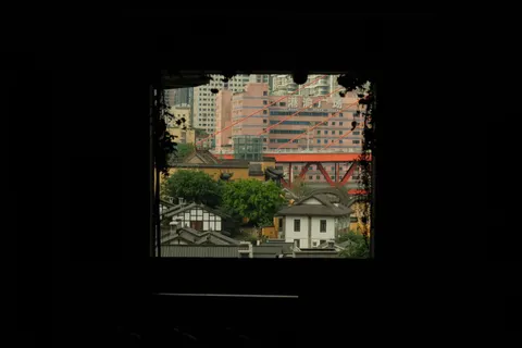 A small red temple is framed through a dark rectangular opening.