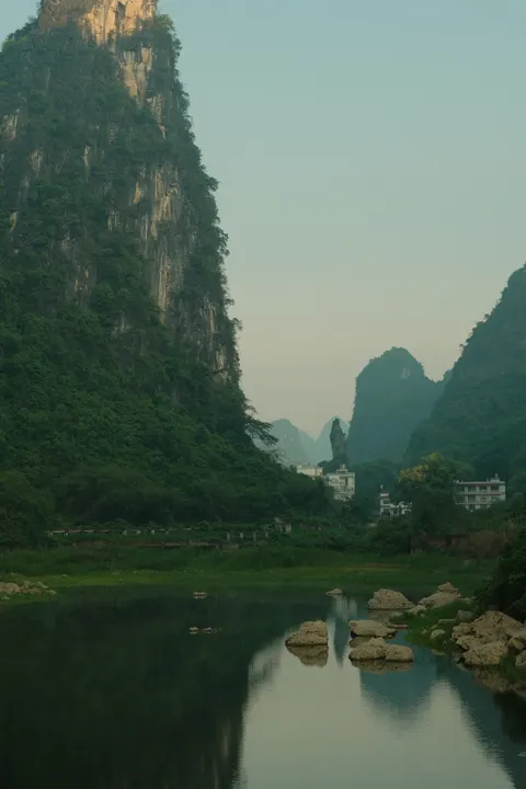 Karst peaks reflect in a calm river beneath a hazy Guilin sky.