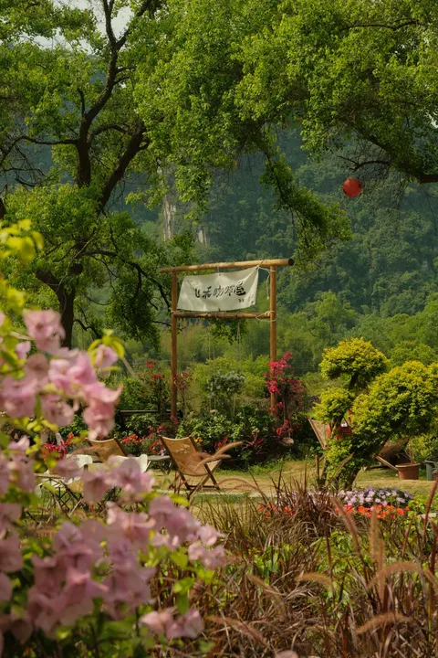 A garden path and pink flowers lead toward green Yangshuo peaks.