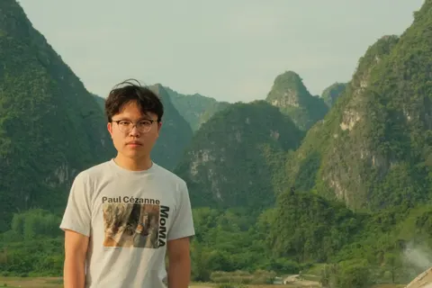 A portrait stands before a valley of dramatic green karst peaks.