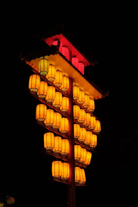 A sculptural cluster of orange lanterns shines against the night.