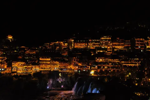 Illuminated buildings cascade down a dark Zhangjiajie hillside.