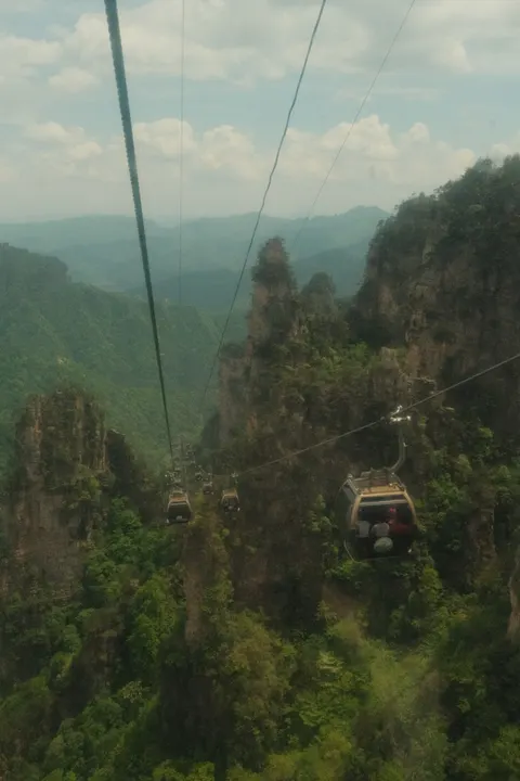 A cable car looks across misty sandstone pillars in Zhangjiajie.