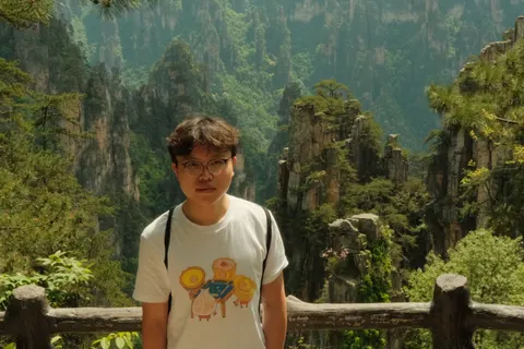 A visitor poses at a railing above the sandstone pillars of Zhangjiajie.