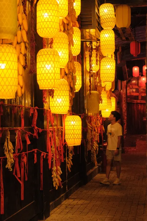 Golden lanterns hang closely together along a narrow passage.