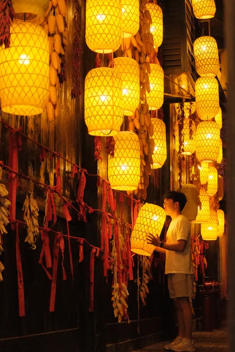 Rows of orange lanterns light a pedestrian lane after dark.