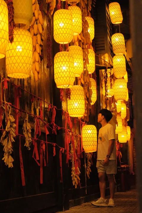 A corridor of glowing lanterns recedes into the night.