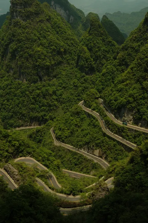 Hairpin roads zigzag across a steep green Zhangjiajie slope.