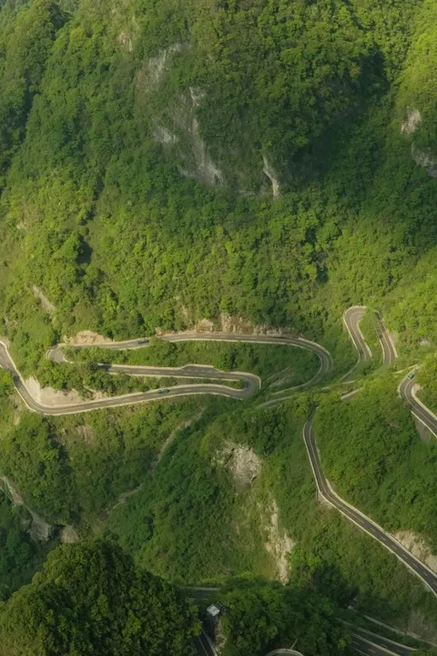 Multiple switchbacks descend through the green mountain landscape.