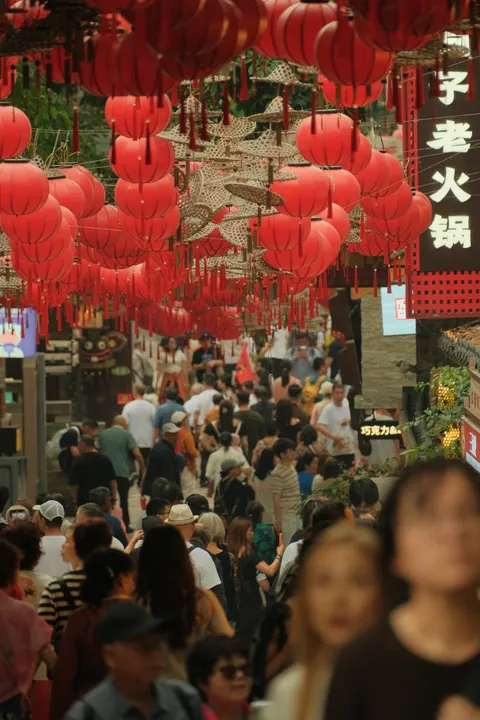 Crowds pass beneath rows of red lanterns in Chongqing.