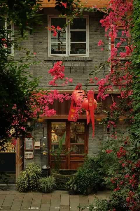 Red flowers climb a pale historic facade in Chongqing.