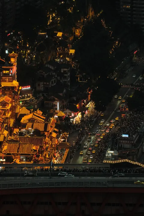 A steeply lit city street descends through Chongqing at night.