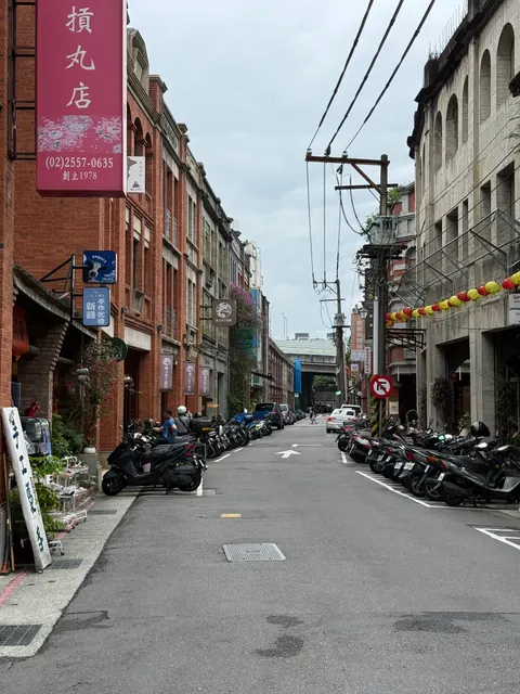 Scooters line a quiet urban lane beneath overhead wires in Taipei.