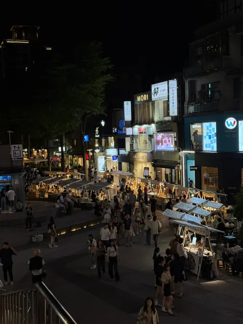 Night market crowds gather beneath illuminated signs in Taipei.