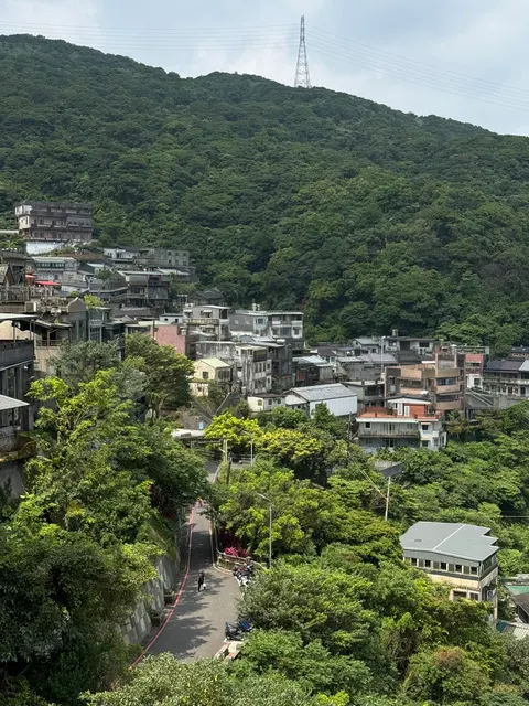 A hillside neighborhood spreads below a green ridge on Taiwan's north coast.