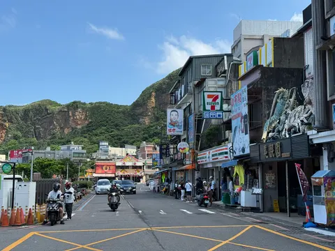 Scooters and storefronts line a coastal town street in northern Taiwan.