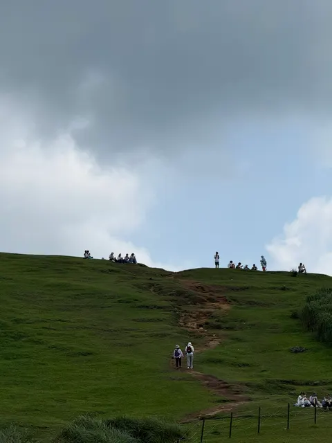 Hikers climb a broad windswept grassland on Taiwan's north coast.