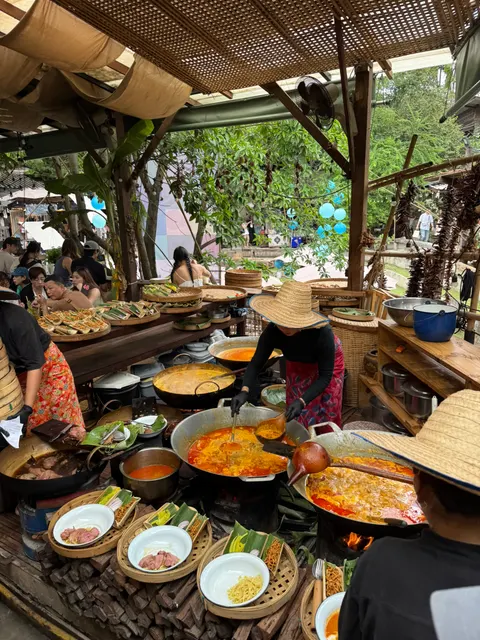 A table overflows with shared Thai dishes at an outdoor meal.