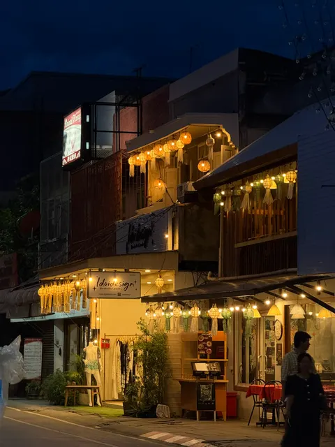 A warmly lit wooden guesthouse stands against the Chiang Mai night.