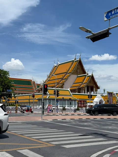 A Bangkok temple's orange roof gleams beneath a clear blue sky.