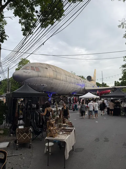 Shoppers browse beneath a large fish sculpture at a Bangkok market.