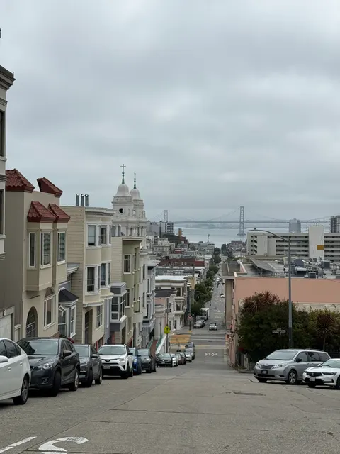 A steep San Francisco street descends toward a distant white church.