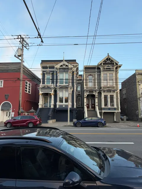 Ornate Victorian facades stand behind parked cars in San Francisco.