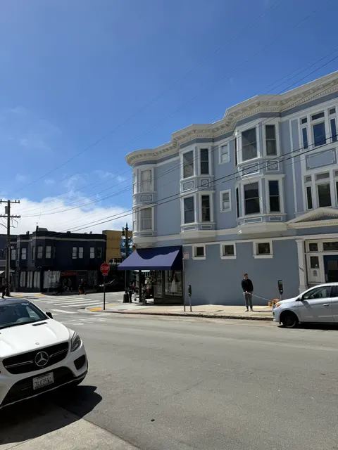 A pale blue corner building faces a quiet San Francisco intersection.