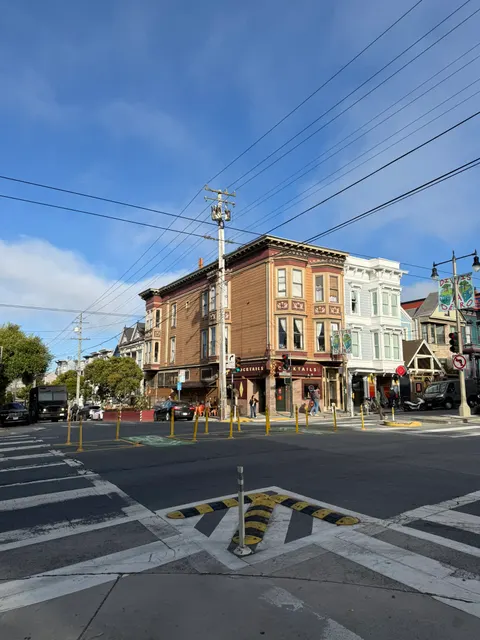 Colorful corner buildings meet beneath overhead wires in San Francisco.