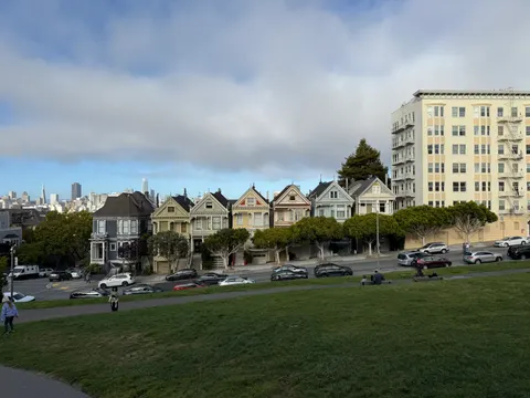 A row of Victorian homes faces a broad green lawn in San Francisco.