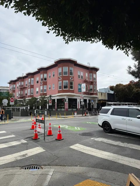 A red corner building faces a marked San Francisco crosswalk.